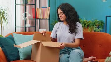 Angry dissatisfied shopper Indian woman unpacking parcel feeling upset and confused with wrong mistake delivery from an online store, bad quality broken purchase at home. Girl indoors in room on couch video