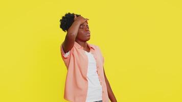African American woman holds head swaying unsteadily with a disoriented expression and visible struggle. Black girl isolated on yellow background highlights dizziness, imbalance, and physical weakness video