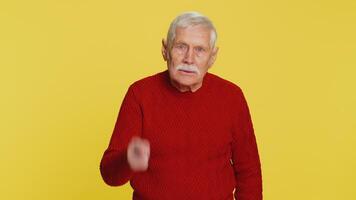 Quarrel. Displeased aggressive unhappy senior old man gesturing hands with irritation and displeasure, blaming scolding for failure, asking why this happened. Elderly grandfather on yellow background video