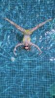 Aerial top-down view of woman in yellow bikini floating in tropical pool with clear blue water. Perfect for relaxation, summer lifestyle, and travel content. video