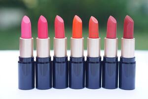 Row of vibrant lipsticks in various shades of pink, orange, and red displayed in elegant black and gold tubes. Concept, beauty, fashion, and makeup diversity, different mood, personality, and style photo