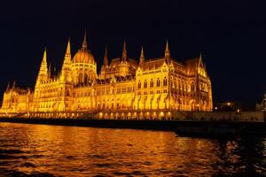 Hungarian Parliament Building illuminated at night with golden lights reflecting on the Danube River in Budapest, photographed on April 14, 2024 photo