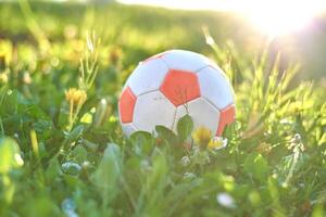 Soccer ball on green grass in a sunny spring setting. Sports theme with a focus on nature and outdoor play. photo