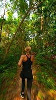 Dynamic FPV drone shot of woman running through lush tropical jungle path, capturing fitness, freedom, and nature in motion. Ideal for wellness, travel, and adventure themes. video