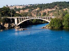 Bridge Over River With Hills And Kayaks photo