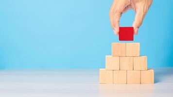 Businessman hand placing or pulling Red wooden block on the building. Business planning, Risk Management, Solution, strategy, different Concepts photo