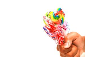 Hand holding a bundle of colorful lollipops against a plain white background, perfect for a sweet treat advertisement photo