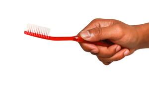 A hand holding a red toothbrush against a plain white background in studio lighting, a simple hygienic concept photo