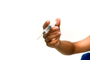 Dark-skinned hand holding a syringe against a pristine white background, poised for medical action photo