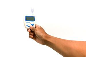 Close up of a person holding a glucometer device against a white background, isolated shot showing device photo