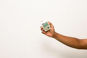 Hand holding a digital glucometer for blood sugar testing on a white background photo