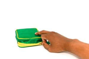 Unzipping a Small Green and Yellow Bag on White Background, hand in action opening photo