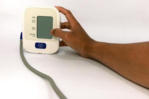 Close-up of person using a digital blood pressure monitor on a white surface highlighting healthcare technology photo