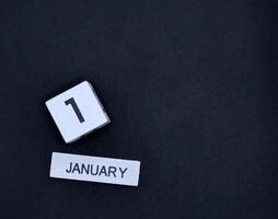 Wooden calendar, January 1, New Year's Day on black background photo