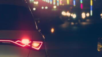Abstract and blurred image of rear side cars on the road with light break atnight. Blurred background of light of the multi colored light bulbs on the roadside in front. photo