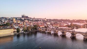 The morning light casts a warm glow over Prague, illuminating the Vltava River and the historic architecture, including Charles Bridge and Hradcany Castle, in a breathtaking panorama. photo