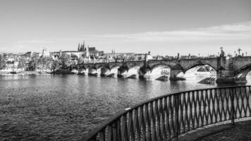 This captivating panorama showcases the majestic Prague Castle overlooking the Vltava River, with the iconic Charles Bridge in the foreground, all in a serene, people-free setting. photo