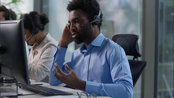Frustrated business callcenter operators African man stressed talking helpline call center multiethnic Caucasian Indian workers headset typing computer customer service sell online sales failure upset video