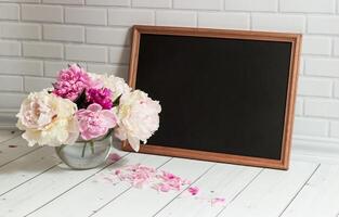 Empty chalkboard with place for text and peonies bouquet in vase photo