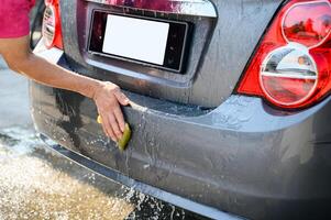 Man worker washing and rubbing with sponge on car photo