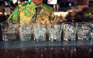 Cocktail glass with ice cubes on counter bar in nightclub photo