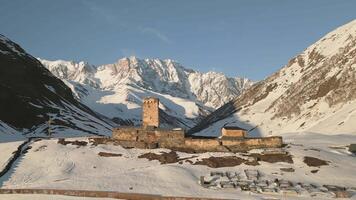 Aerial Ancient Lamaria Monastery in snowy highland valley, surrounded by Caucasus peaks, part of UNESCO-listed Upper Svaneti region video