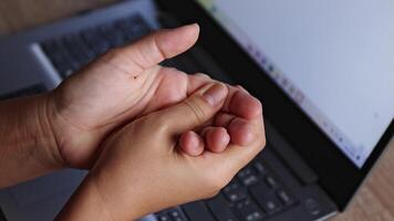 hand and finger or wrist pain, sore fingers, numbness in fingertips, close-up of hand squeezing numb fingers with laptop in background. concept of hand numbness, nerve pain, carpal tunnel syndrome video