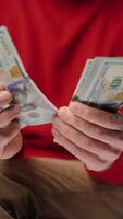 Man counting US Dollar bills, closeup. Vertical video