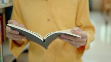 Young man turning a page of book in public library. video
