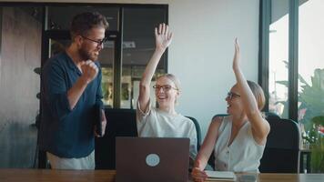 Happy business team exchanging high fives and celebrating successful completion of project in modern office workspace, radiating enthusiasm and collaboration. Successful team celebrates victory video