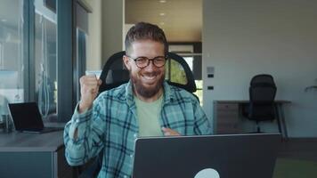 feliz homem de negocios trabalhando em computador portátil dentro moderno escritório, desfrutando dele trabalho enquanto sorridente e noivando com tecnologia, irradiando positividade e confiança dentro brilhante, convidativo espaço video