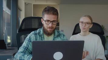 Two sales representative are collaborating on project, sharing ideas and working together on laptop in modern office environment, engaging in productive teamwork and problem solving video