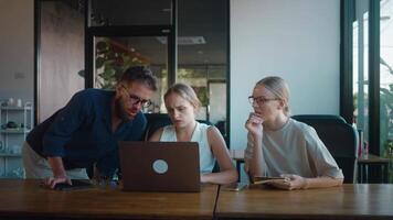Brainstorm over serious project are collaborating on project, gathered around laptop in a contemporary office setting, engaging in problem solving and strategic discussion. Brainstorm video