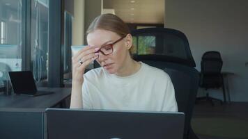 Office worker sitting at modern desk, using laptop and gesturing while explaining project details during an engaging online meeting in dynamic workplace environment. Online meeting with customers video