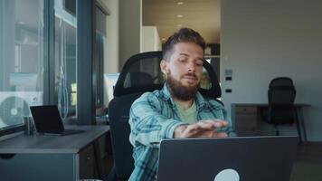 Tired office worker removing glasses and leaning back in chair after completing tasks on laptop, enjoying moment of relaxation in modern corporate workspace. Office burnout concept video