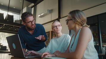 Three colleagues brainstorming discussing a project, collaborating around laptop in modern office environment, sharing ideas and working together. Office brainstorming to obtain highest productivity video