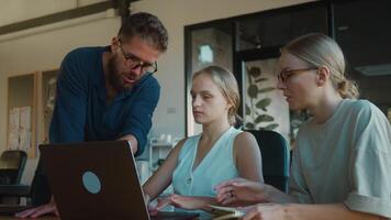 Three colleagues discussing project in front of laptop, exchanging ideas and collaborating in bright, modern office environment, fostering teamwork and strategic planning. Concept team project video