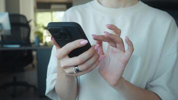 Social media manager using smartphone, browsing internet, checking social media, or texting messages in modern workplace, close up on hands holding mobile device. Social media manager in work video