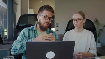 Two business colleagues engaging in conference on laptop in bright office, gesturing and discussing important work related matters, fostering collaboration and teamwork video