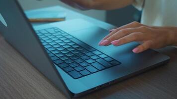 stänga upp kvinnors händer med rosa manikyr skriver på bärbar dator tangentbord och navigerande pekplatta, engagerande i avlägsen arbete från mysigt Hem kontor miljö. skriver på dator tangentbord video