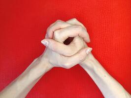 Hands clasped together against a bright red background displaying a sense of calmness and focus during a moment of contemplation photo