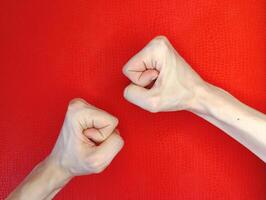 Hands with clenched fists against a vibrant red backdrop symbolizing determination and strength in an artistic display of emotion photo
