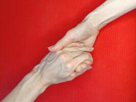 Two hands engaged in a firm handshake on a vibrant red background, symbolizing agreement and connection between individuals photo