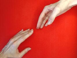 Hands reaching towards each other on a vibrant red surface representing connection and communication in a serene environment photo