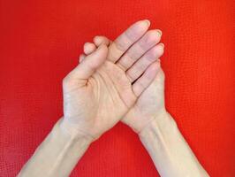 Hands in a gesture of unity resting against a vibrant red background during a calming moment of reflection photo