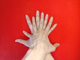 Hands placed together on a vibrant red background showcasing unity and creativity during a collaborative workshop photo