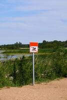 A Notice Sign That Clearly Warns That Swimming is Absolutely Forbidden Near the Waterbody photo