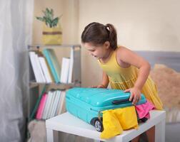 A child tries to close suitcase with things for a vacation photo