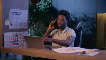 African American architect business man designer businessman in office talk mobile phone night evening online work laptop ethnic guy engineer employee overtime consultation call discuss design project video