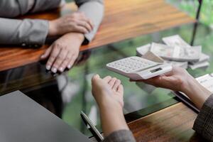 two people sitting at a table with a calculator photo